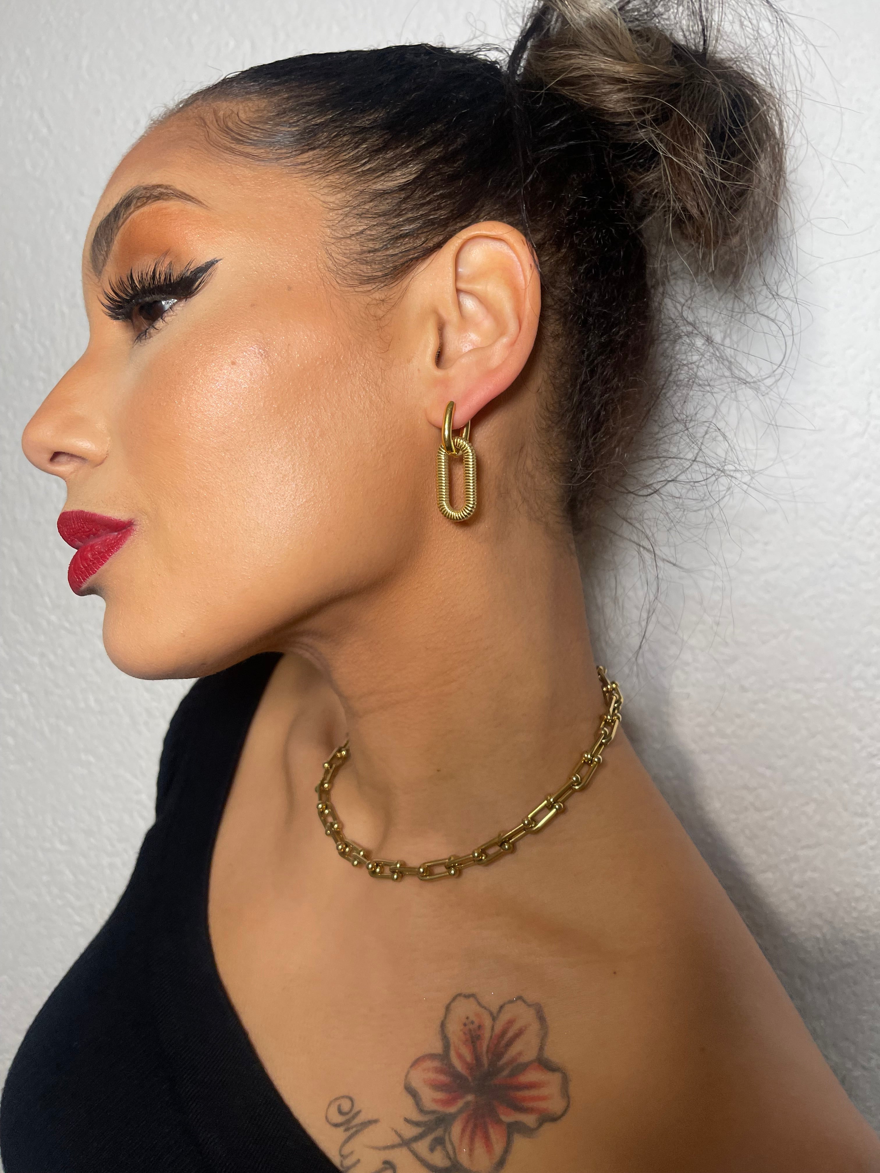 NAOMI dangles gold-tone oval link earrings on woman.