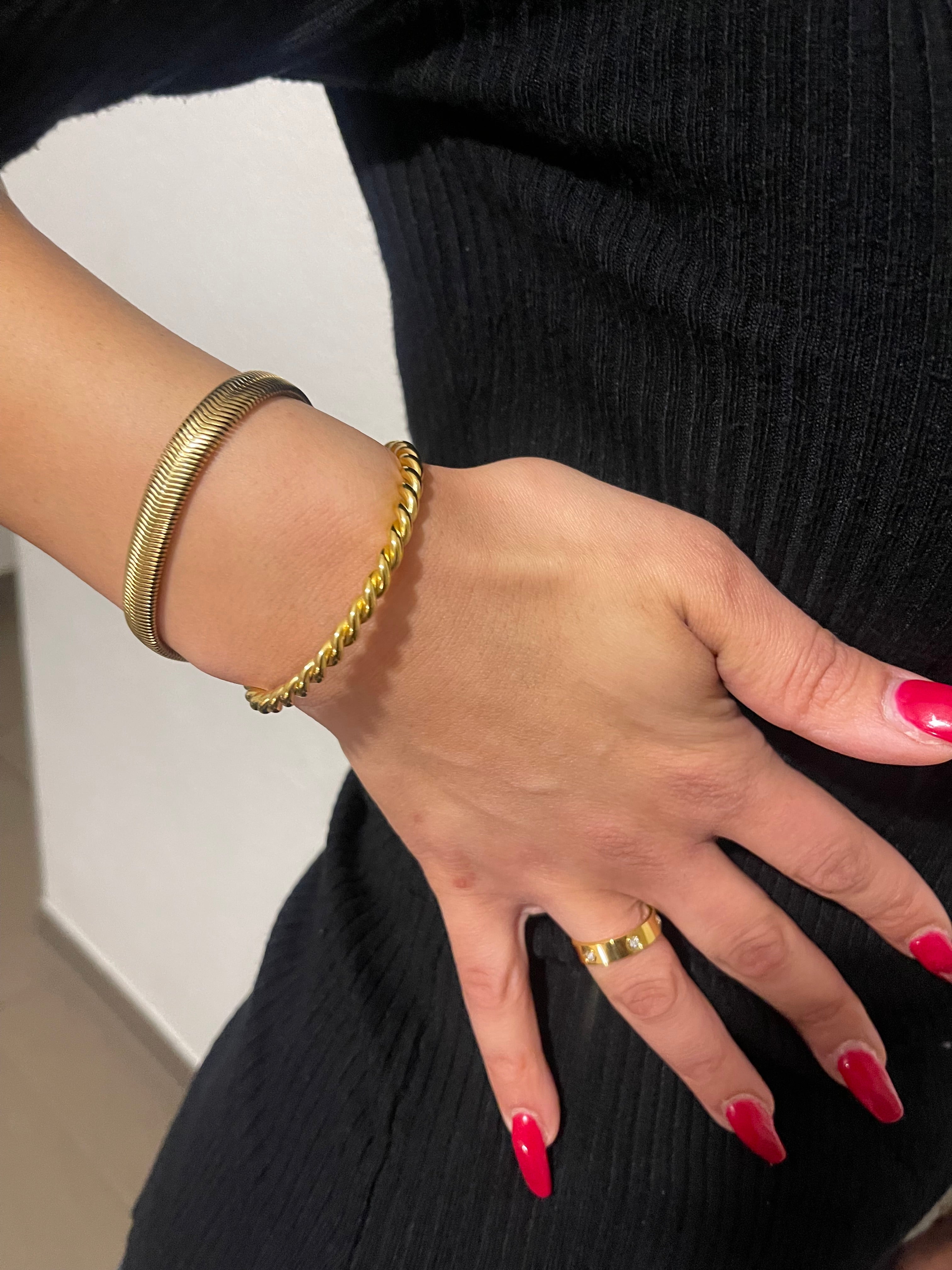 Gold twist bangle with polished finish on wrist, showcasing elegant and minimalistic design.