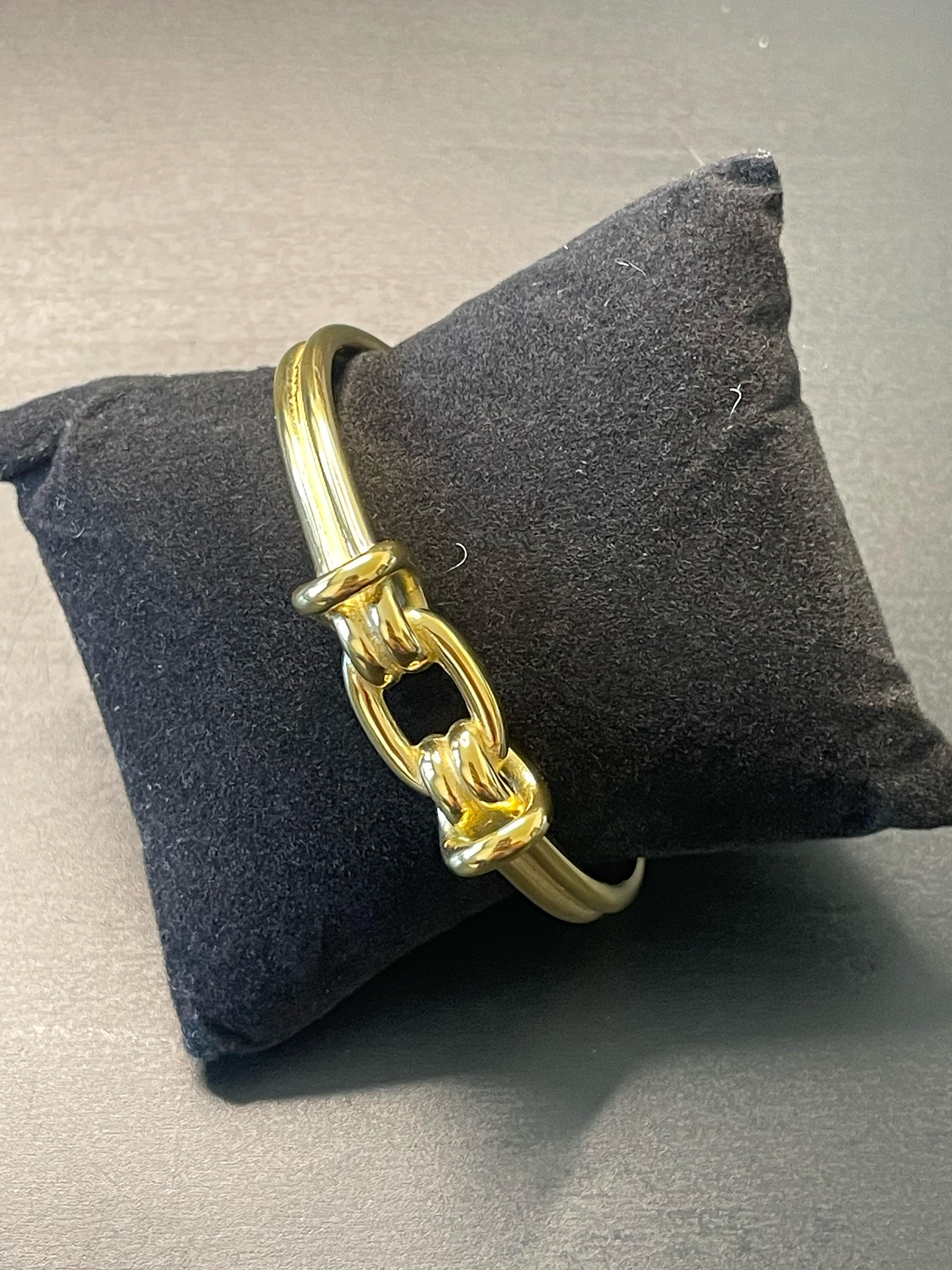 CHLOE Gold Bangle with chain-link centerpiece on black cushion.