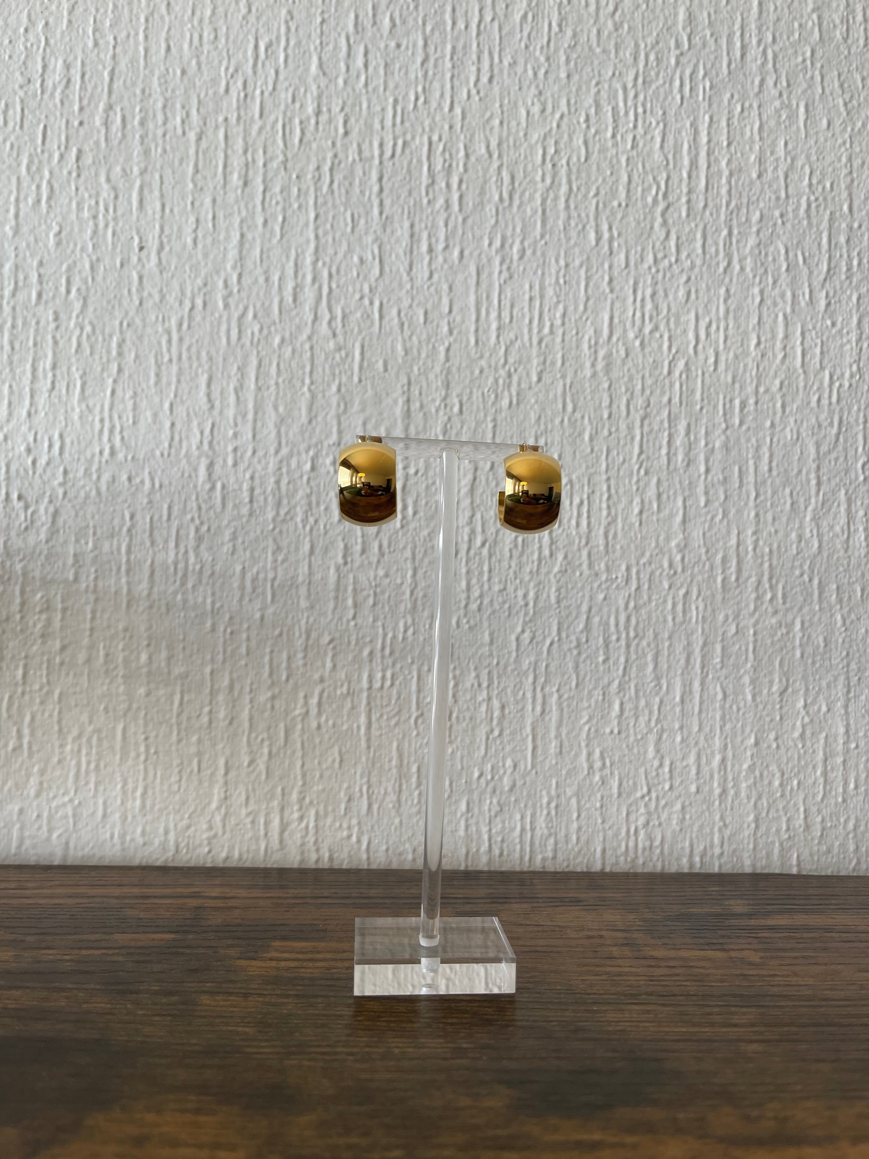 CRISTINA Tiny C-Shaped Hoops in gold on display stand, showcasing minimalist and elegant design.