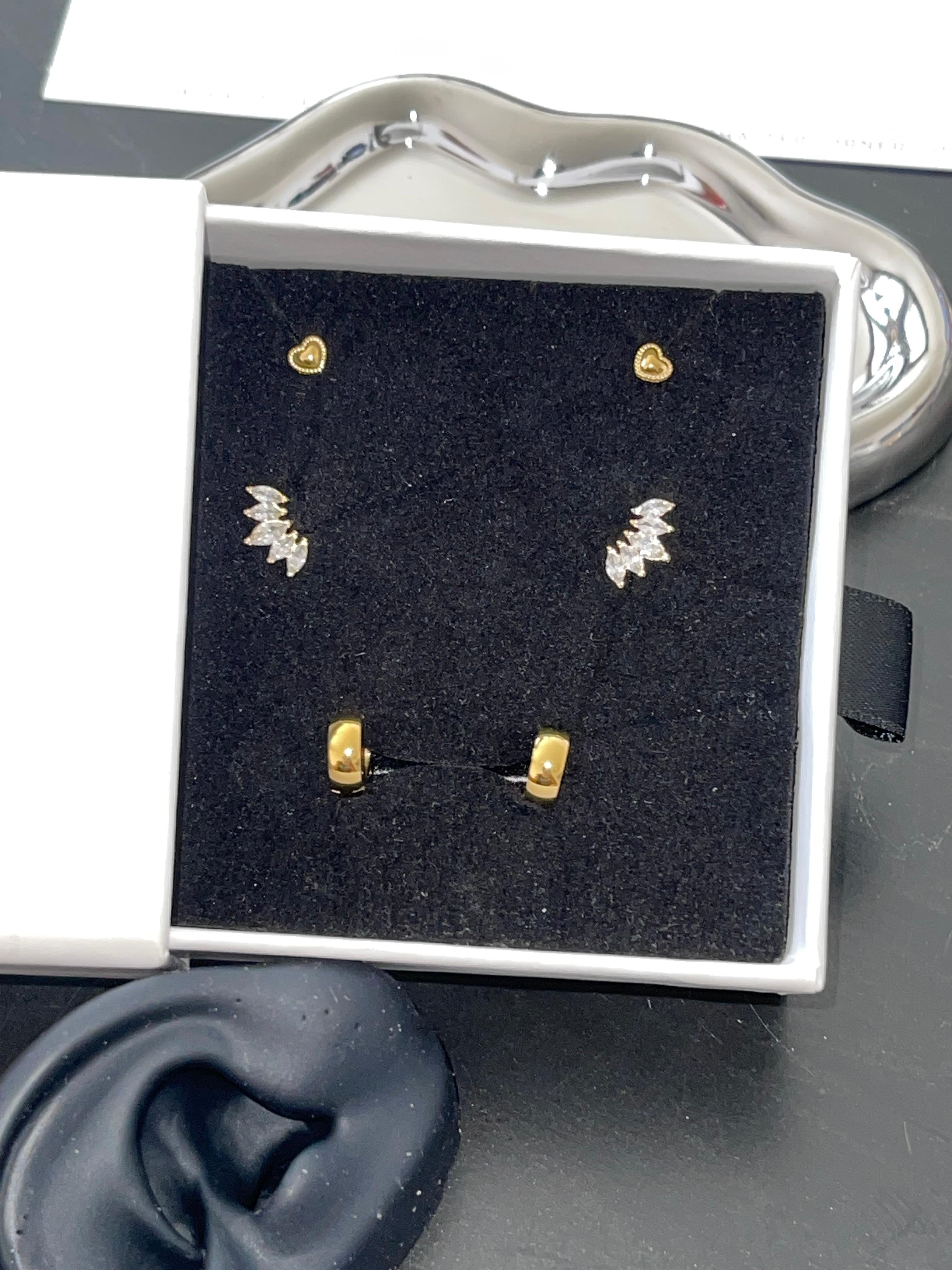 Aurelie Trio Set with gold heart studs, cubic zirconia pavé wing studs, and polished gold mini hoops in a jewelry box