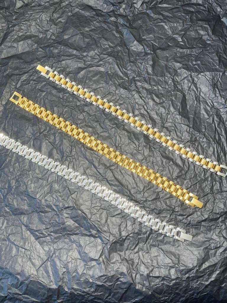 The Enzo Bracelet stainless steel geometric links in gold and silver with fold-over clasp on textured background