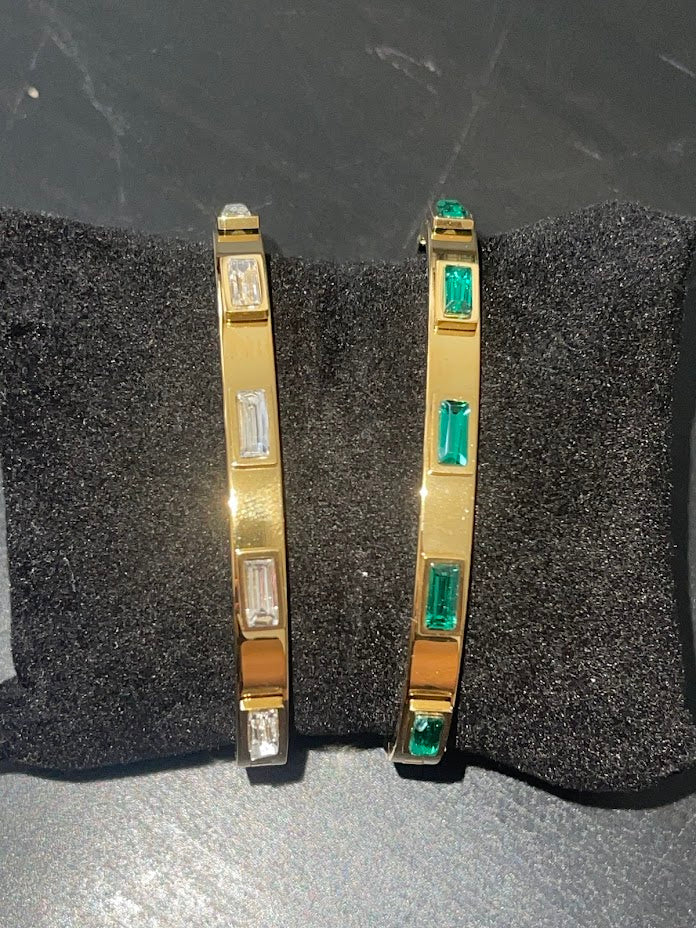 Set of sleek Taylor Bangles with 18k gold plating and baguette-cut cubic zirconia stones in emerald green and white diamond colors.