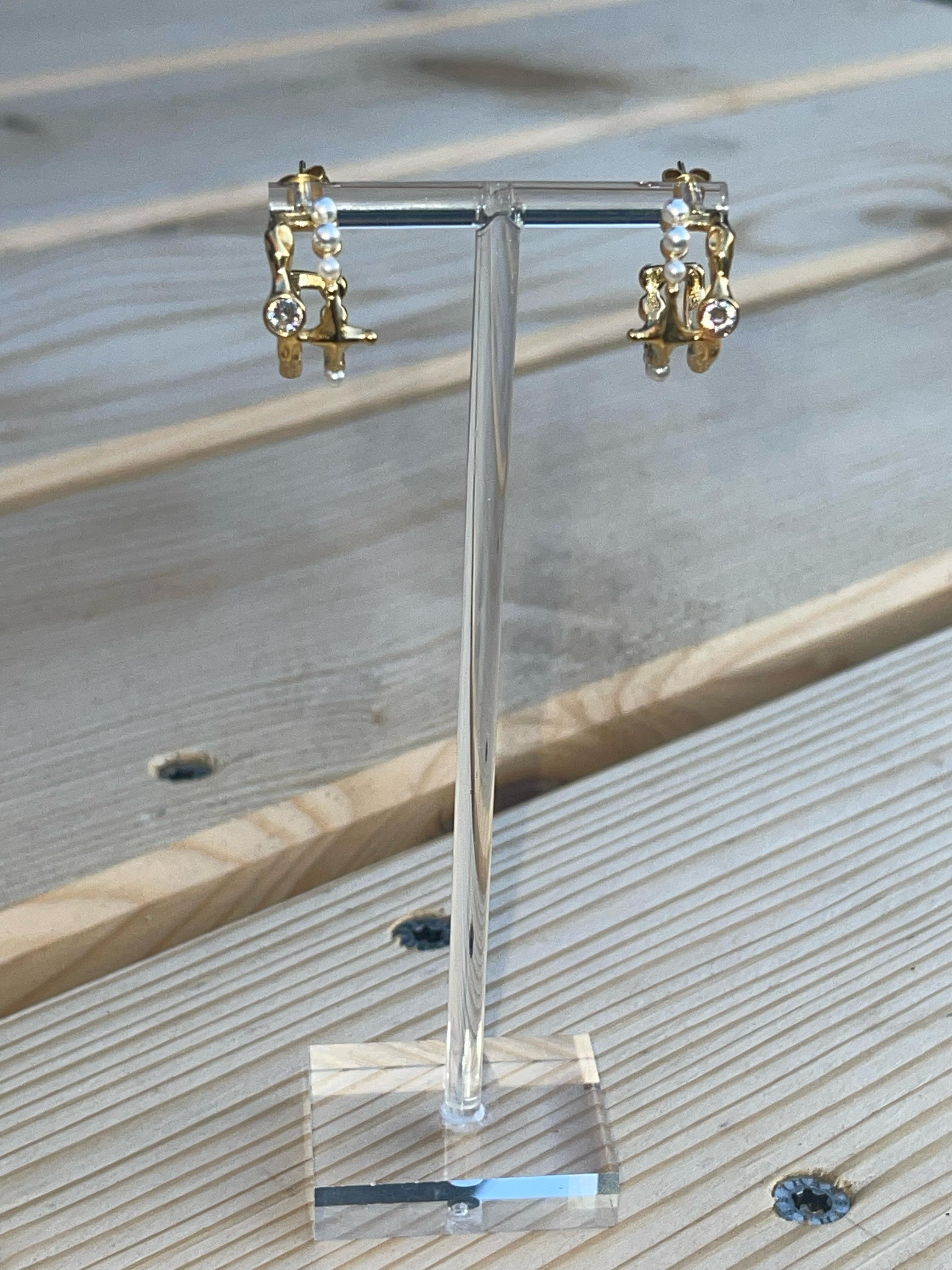 Gold-tone hoop earrings with faux pearls, crystal drops, abstract charm accents, and 18k gold plating.