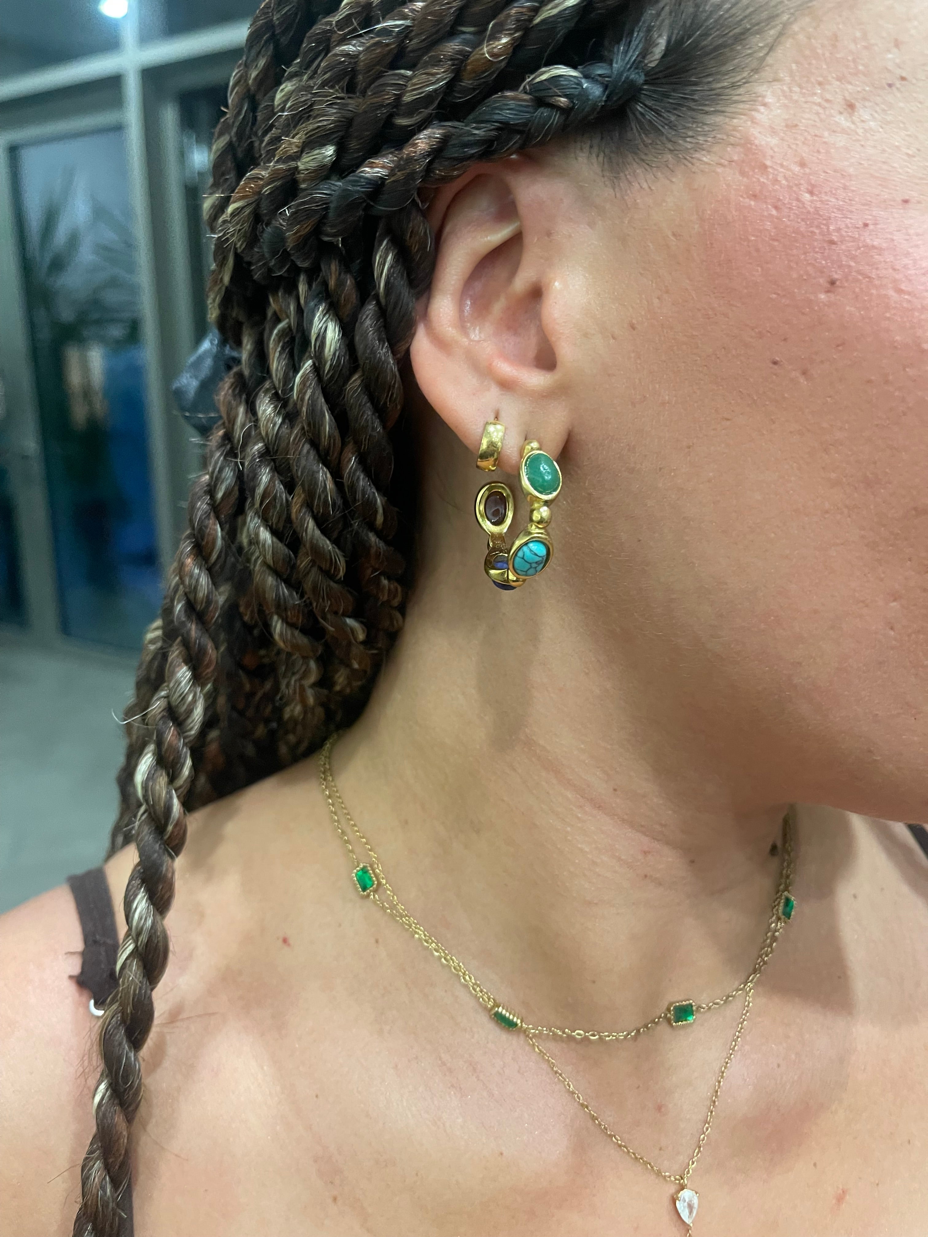 Close-up of a woman's ear wearing Gina Earrings with green agate, turquoise, and lapis stones in an 18k gold-plated vertical design.
