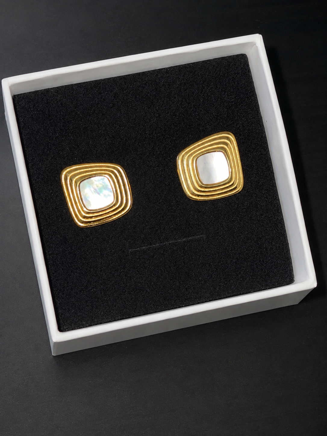 Close-up of SLOANE Square Statement Studs earrings with modern black enamel geometric design on white background