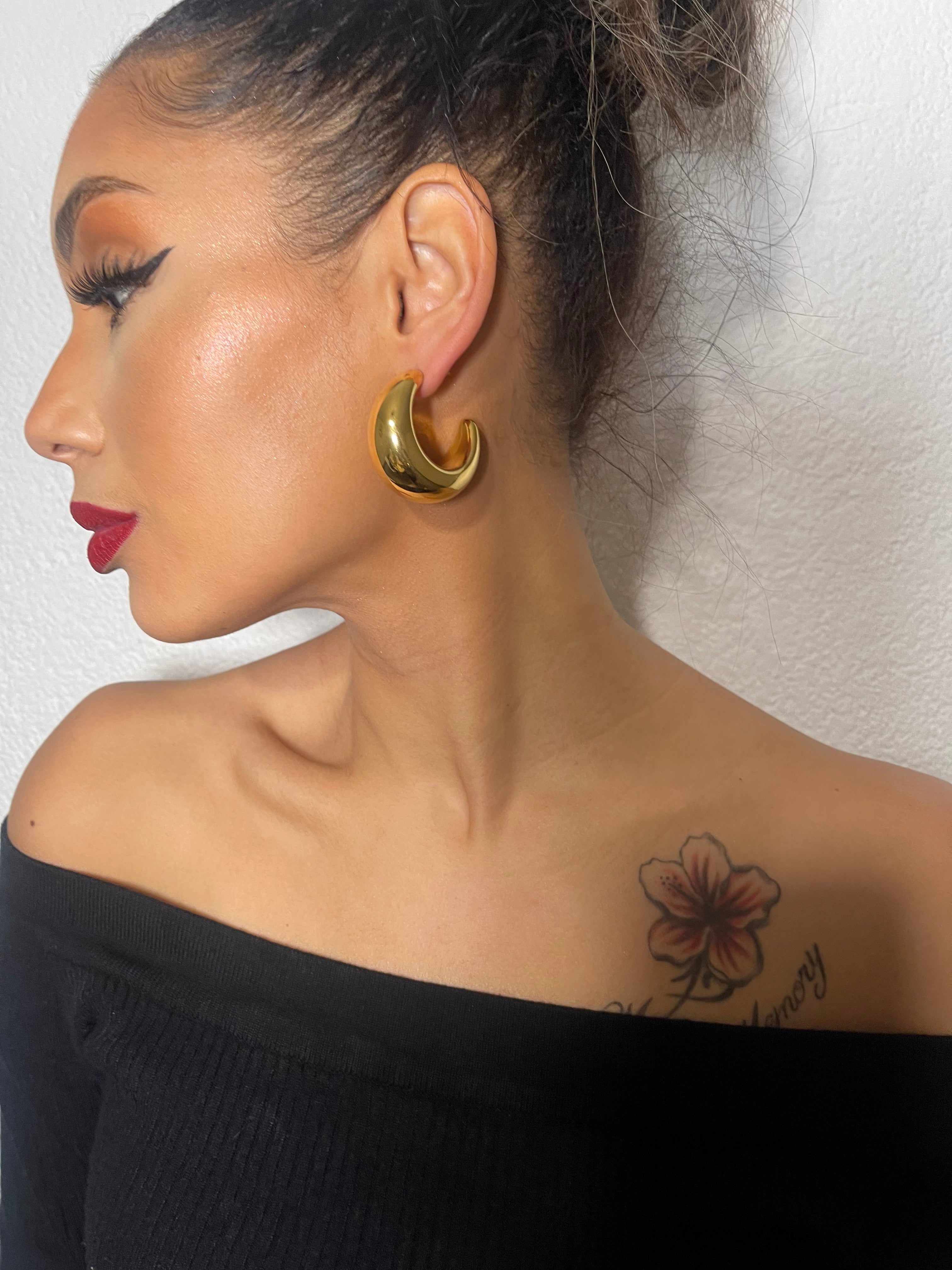 ANGELA Moon-Shaped thick hoops in gold, worn by a model with an off-shoulder black top.